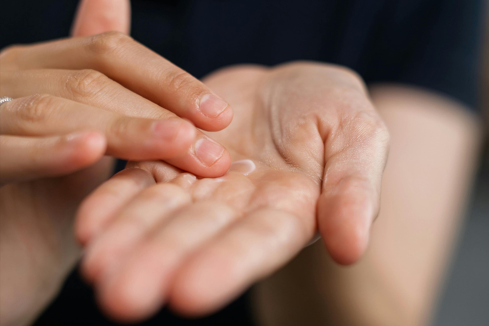 Eine Person verreibt Creme in einer Hand.