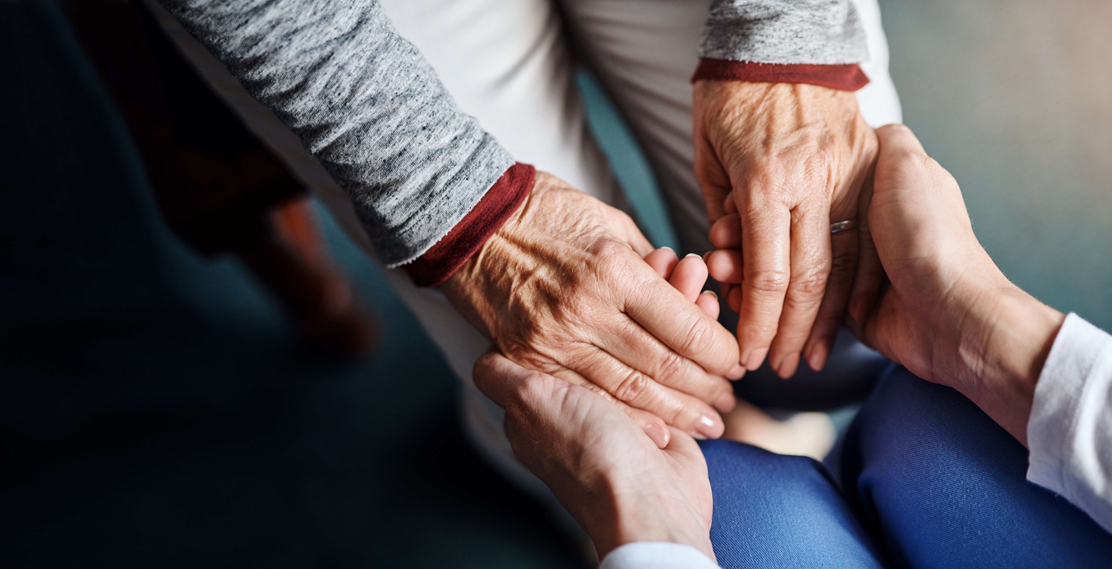 Pflegende h&auml;lt tr&ouml;stend die H&auml;nde einer &auml;lteren Person